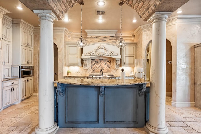 kitchen with stone tile floors, decorative columns, arched walkways, and light stone counters