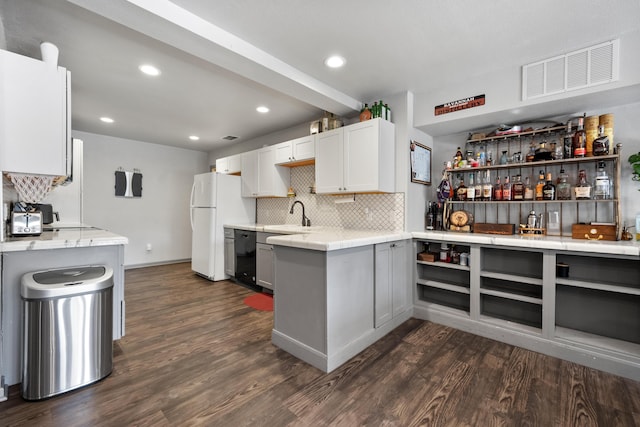 kitchen with a sink, visible vents, freestanding refrigerator, dark wood finished floors, and backsplash