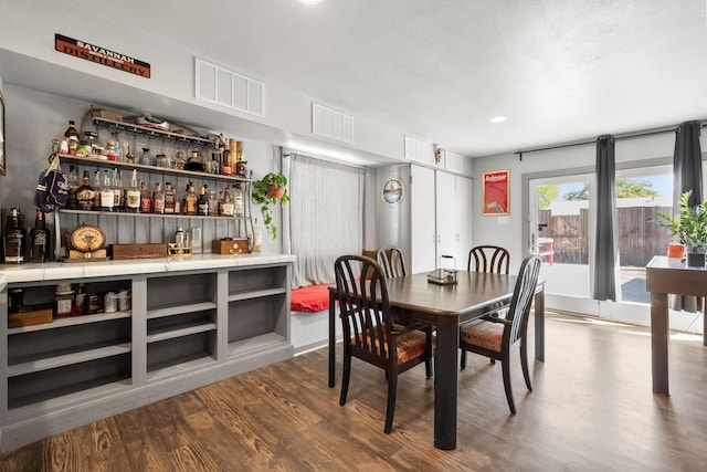 dining room with a dry bar, wood finished floors, visible vents, and recessed lighting