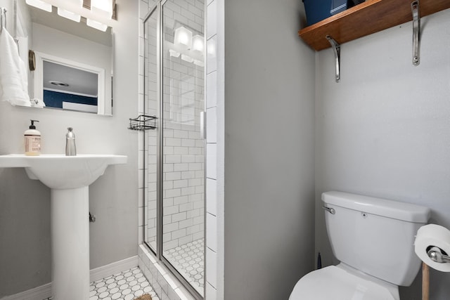 full bathroom featuring a sink, toilet, a stall shower, and baseboards