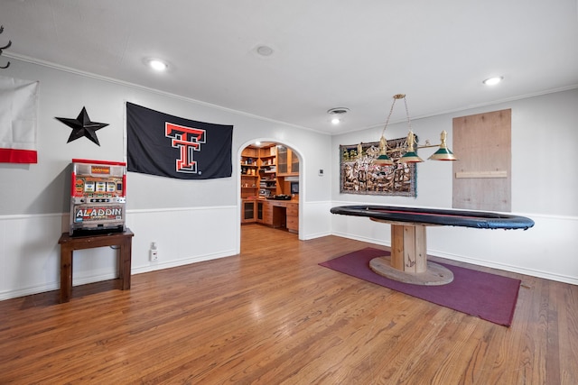 rec room featuring wainscoting, wood finished floors, and crown molding