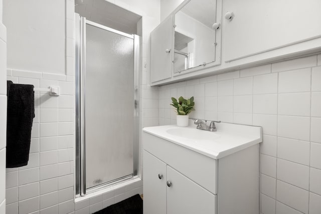 full bath featuring tile walls, a stall shower, and vanity