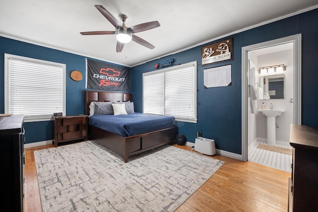 bedroom featuring baseboards, ornamental molding, light wood finished floors, and ensuite bathroom