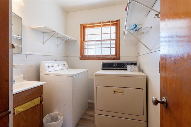clothes washing area with separate washer and dryer and tile walls