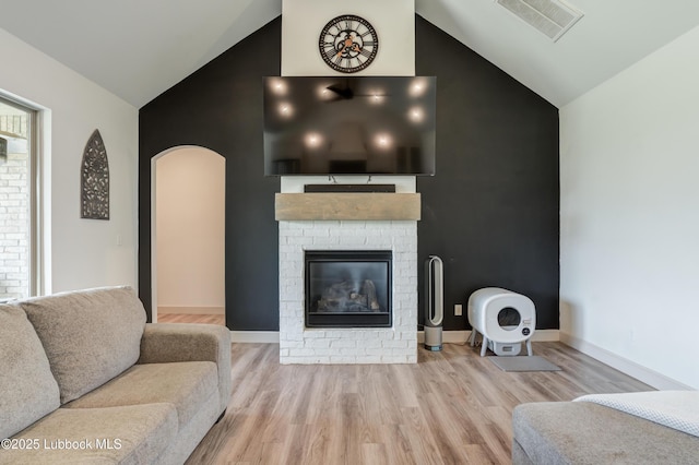 5713 116th St, Lubbock, TX 79424 - living area featuring high vaulted ceiling, wood finished floors, a brick fireplace, arched walkways, and baseboards
