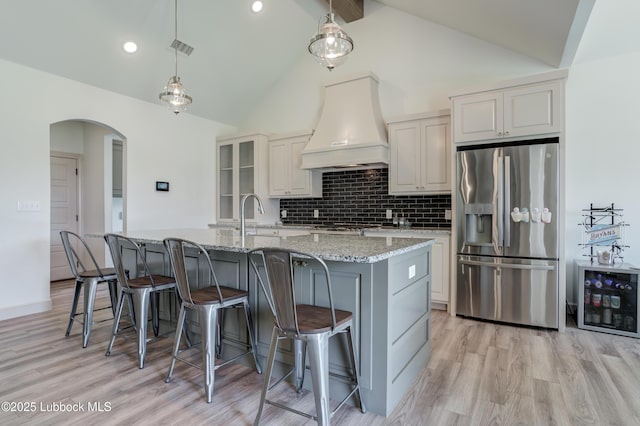 5713 116th St, Lubbock, TX 79424 - kitchen featuring stainless steel fridge, custom exhaust hood, light wood-style floors, decorative backsplash, and beamed ceiling