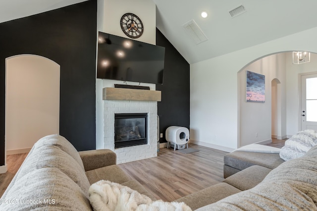 5713 116th St, Lubbock, TX 79424 - living room with arched walkways, lofted ceiling, a fireplace, wood finished floors, and baseboards