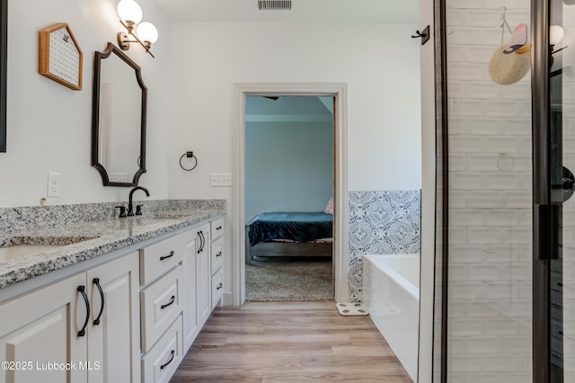 5713 116th St, Lubbock, TX 79424 - full bathroom featuring double vanity, a tub to relax in, wood finished floors, and a tile shower