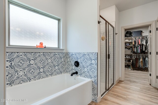 5713 116th St, Lubbock, TX 79424 - bathroom with a shower stall, a bath, wood finished floors, and a spacious closet