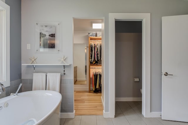 4615 11th St, Lubbock, TX 79416 - bathroom with a soaking tub, tile patterned flooring, tile walls, and a spacious closet