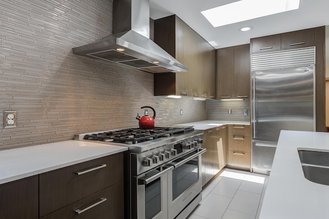 4615 11th St, Lubbock, TX 79416 - kitchen featuring wall chimney exhaust hood, high quality appliances, a skylight, light tile patterned flooring, and light countertops