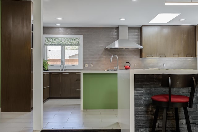 4615 11th St, Lubbock, TX 79416 - kitchen featuring wall chimney exhaust hood, modern cabinets, a skylight, light countertops, and tasteful backsplash