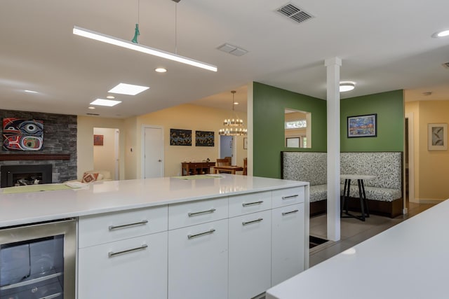 4615 11th St, Lubbock, TX 79416 - kitchen featuring beverage cooler, light countertops, decorative columns, a stone fireplace, and recessed lighting