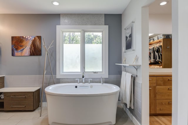 4615 11th St, Lubbock, TX 79416 - bathroom with tile walls, a soaking tub, wainscoting, a walk in closet, and recessed lighting