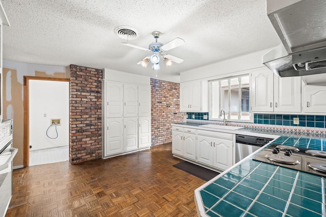 kitchen with tile counters, sink, ventilation hood, and white cabinets