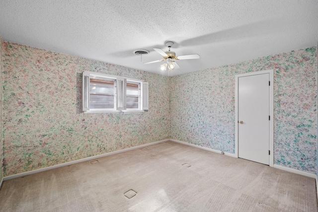 unfurnished room featuring ceiling fan, light carpet, and a textured ceiling