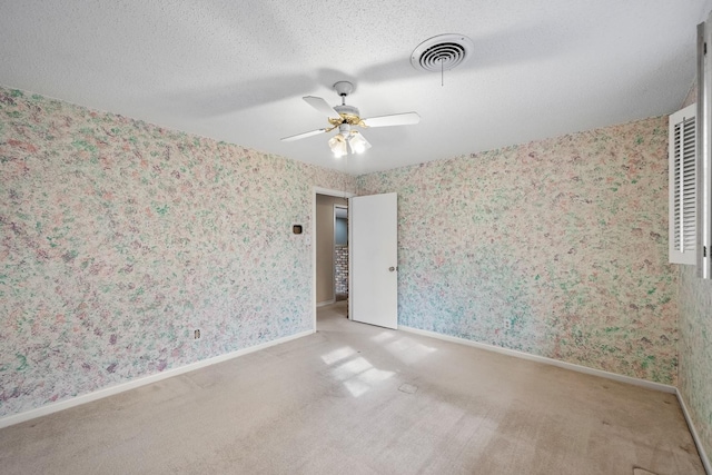 carpeted empty room with ceiling fan and a textured ceiling