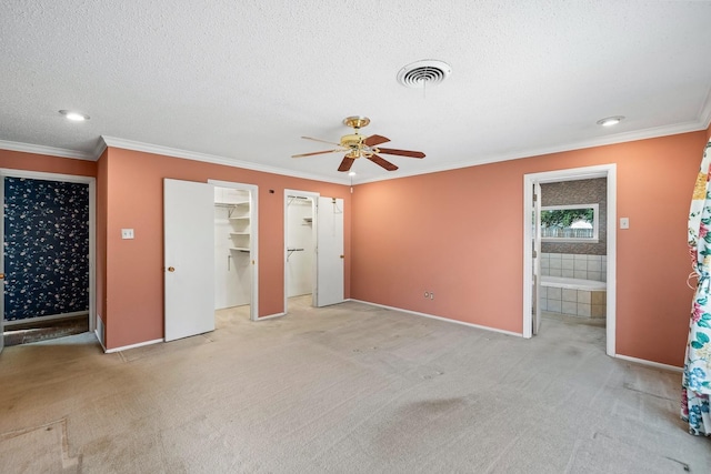 unfurnished bedroom featuring light carpet, ensuite bath, ornamental molding, and a textured ceiling