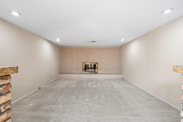 basement featuring a brick fireplace, light colored carpet, and a textured ceiling