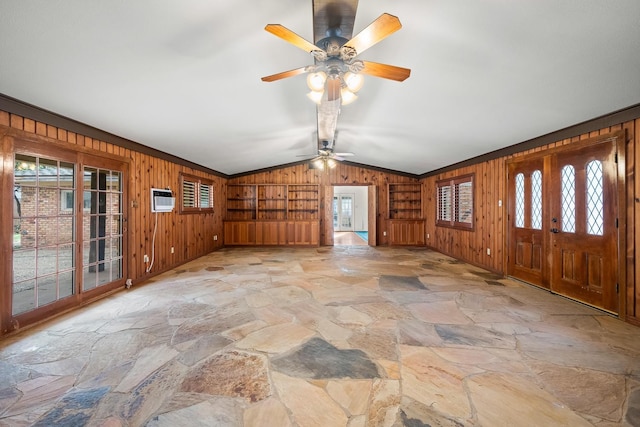 unfurnished living room featuring a wealth of natural light, vaulted ceiling, and wood walls