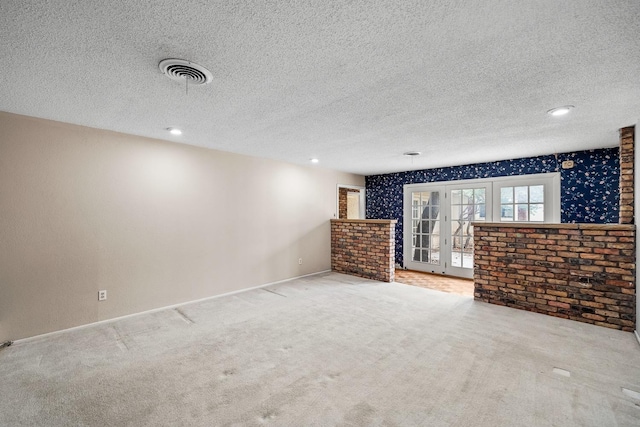 unfurnished living room featuring french doors, light carpet, and a textured ceiling