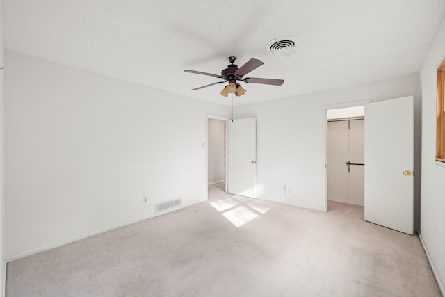 unfurnished bedroom with light carpet, a textured ceiling, ceiling fan, and a closet