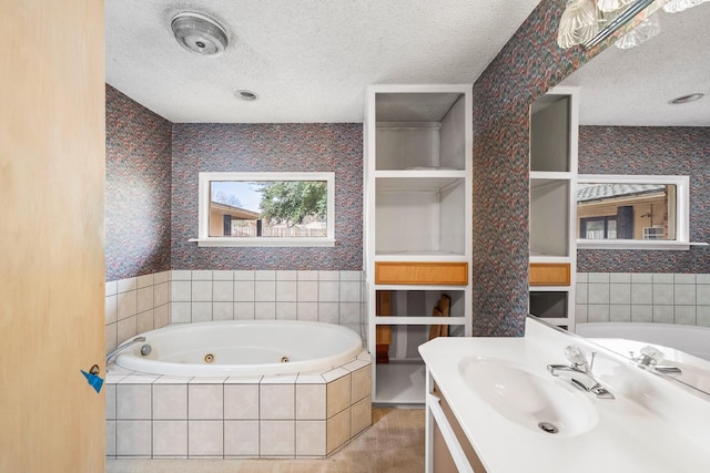 bathroom featuring vanity, a textured ceiling, and tiled tub