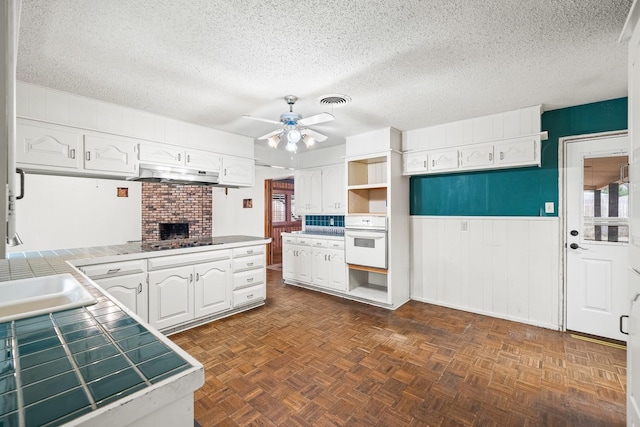 kitchen featuring white cabinetry, plenty of natural light, tile counters, and oven