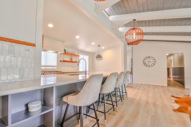 kitchen with lofted ceiling with beams, pendant lighting, backsplash, and a kitchen breakfast bar