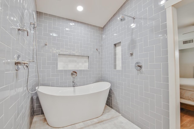 bathroom featuring shower with separate bathtub and tile walls