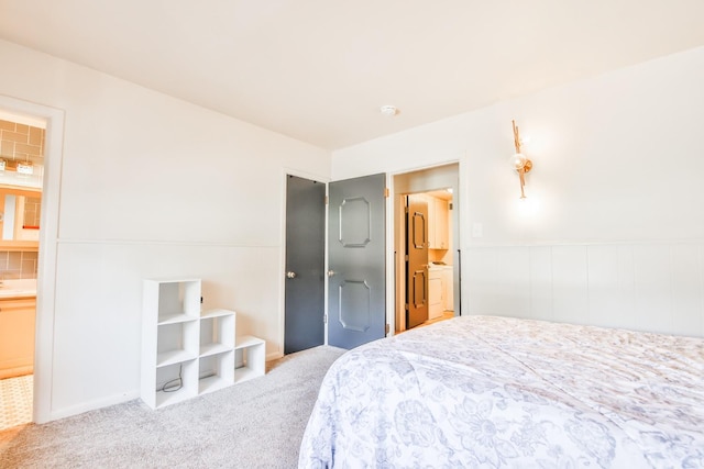 bedroom with connected bathroom, washer / dryer, and carpet flooring