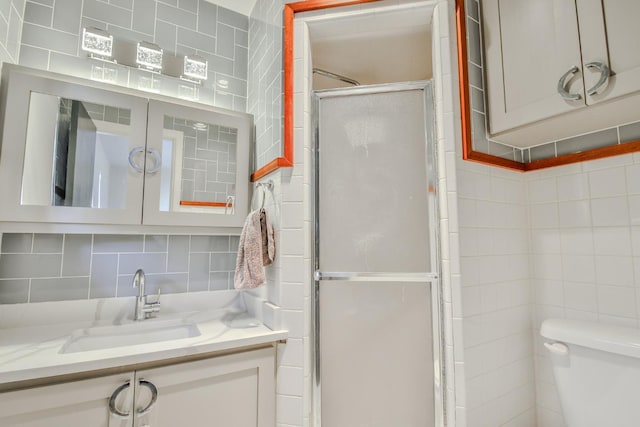 bathroom featuring walk in shower, toilet, tasteful backsplash, tile walls, and vanity