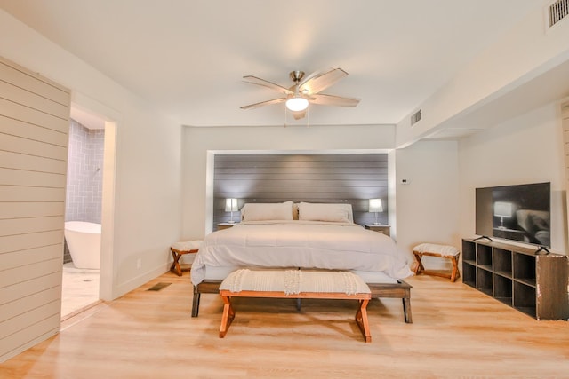 bedroom featuring ceiling fan, ensuite bath, and light hardwood / wood-style flooring