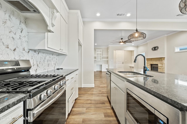 1016 N Genoa Ave, Lubbock, TX 79416 - kitchen featuring appliances with stainless steel finishes, light wood finished floors, a fireplace, ceiling fan, and recessed lighting