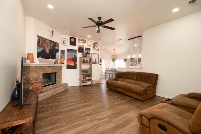 living room with vaulted ceiling, a brick fireplace, hardwood / wood-style floors, and ceiling fan