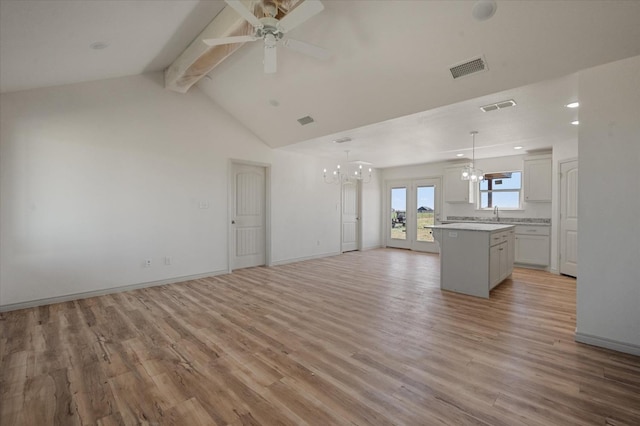 unfurnished living room with vaulted ceiling with beams, ceiling fan with notable chandelier, and light wood-type flooring