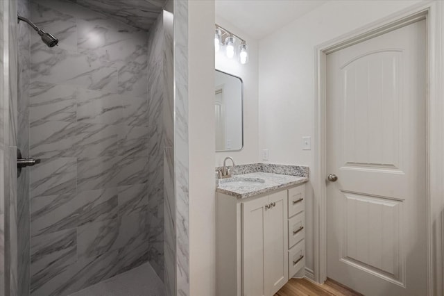 bathroom featuring hardwood / wood-style flooring, vanity, and a tile shower