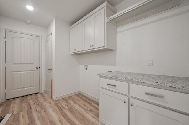 clothes washing area featuring cabinets, washer hookup, and light hardwood / wood-style floors