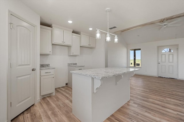 kitchen with light hardwood / wood-style flooring, a center island, hanging light fixtures, and white cabinets