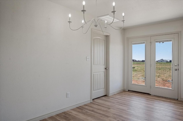 unfurnished dining area with light hardwood / wood-style floors and a notable chandelier