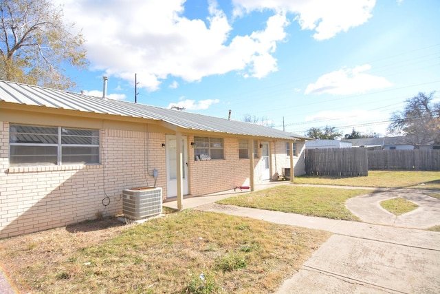 view of front facade with cooling unit and a front lawn