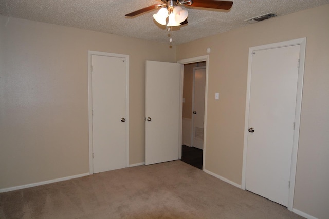 unfurnished bedroom with light colored carpet, a textured ceiling, and ceiling fan