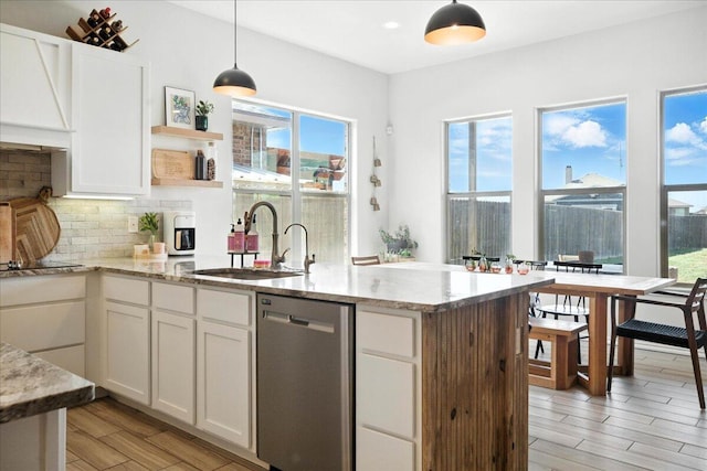 7502 103rd St, Lubbock, TX 79424 - kitchen featuring stainless steel dishwasher, open shelves, backsplash, light stone counters, and light wood-style flooring