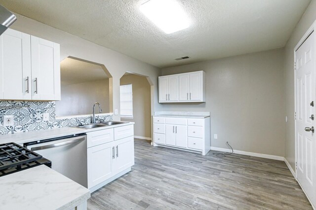 kitchen featuring sink, light hardwood / wood-style flooring, stainless steel dishwasher, and white cabinets