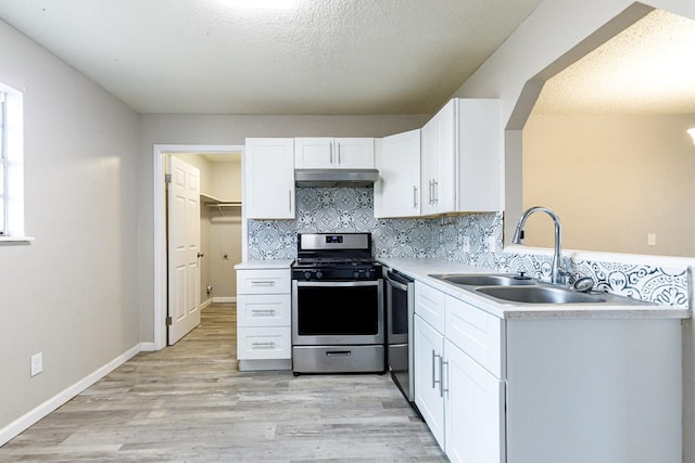 kitchen featuring sink, tasteful backsplash, light wood-type flooring, appliances with stainless steel finishes, and white cabinets