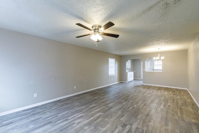 spare room with dark hardwood / wood-style floors, ceiling fan with notable chandelier, and a textured ceiling