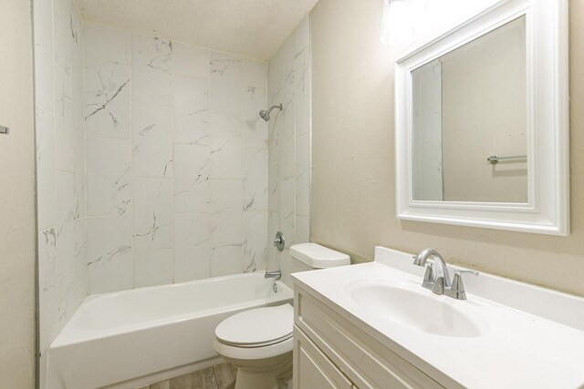 full bathroom with vanity, tiled shower / bath, a textured ceiling, and toilet