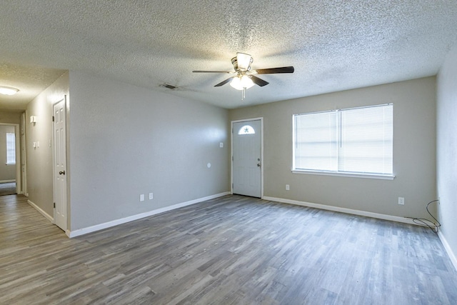 empty room featuring hardwood / wood-style floors, a textured ceiling, a wealth of natural light, and ceiling fan