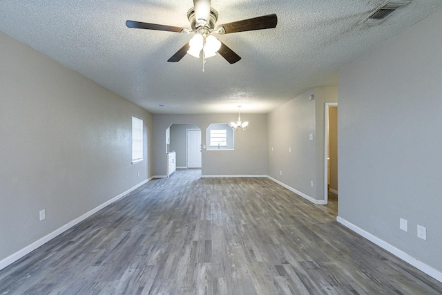 empty room featuring dark hardwood / wood-style flooring, ceiling fan with notable chandelier, and a textured ceiling