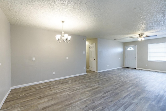 empty room with hardwood / wood-style flooring, ceiling fan with notable chandelier, and a textured ceiling